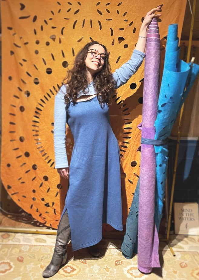 happy woman standing in front of art backdrop wearing a cool comfortable dress