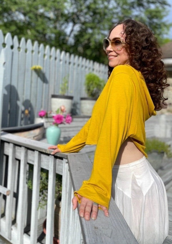 Woman in a super soft sunproof hoodie, gold color wearing big sunglasses looking happy