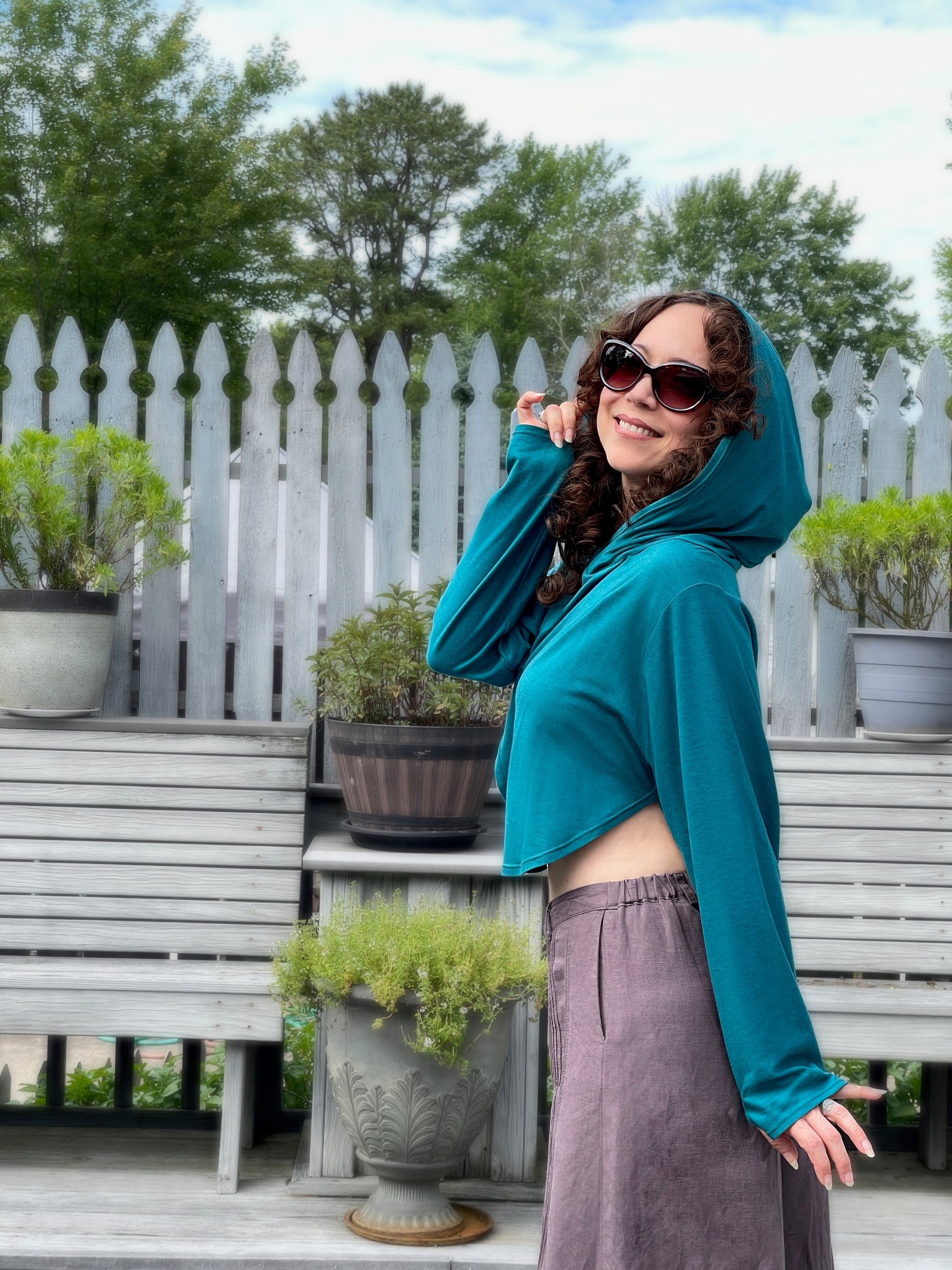 Woman in teal  cute cropped sun safe upf 50+ hoodie for travel , with extra large hood and glovelettes for hand protection